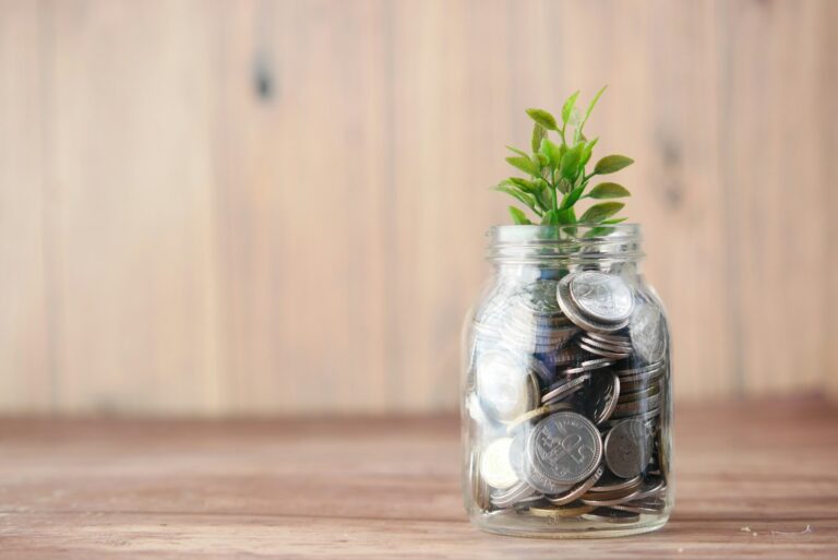 un pot en verre rempli de pièces de monnaie et une plante